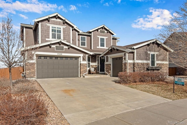 craftsman inspired home with concrete driveway, fence, and stone siding