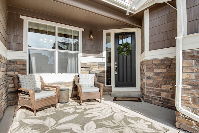 view of exterior entry with covered porch and stone siding