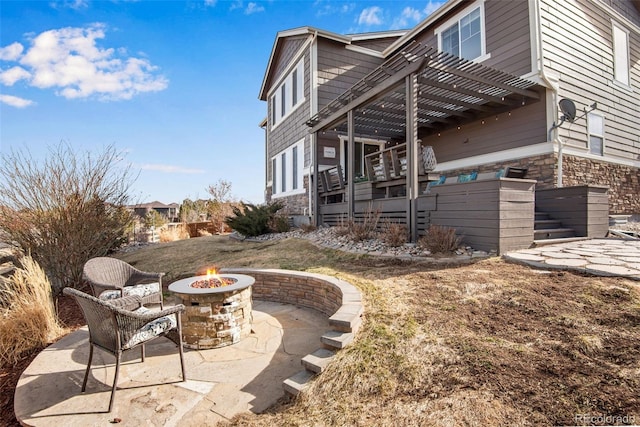 view of home's exterior with a pergola, stone siding, an outdoor fire pit, stairway, and a patio area