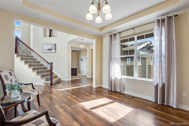 entryway featuring an inviting chandelier, stairway, wood finished floors, and visible vents