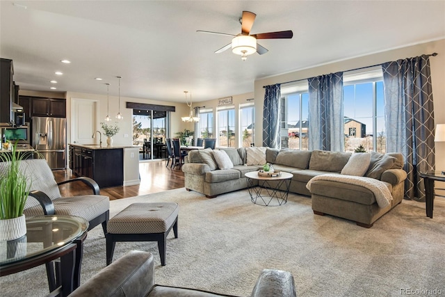 living room featuring ceiling fan with notable chandelier, wood finished floors, plenty of natural light, and recessed lighting