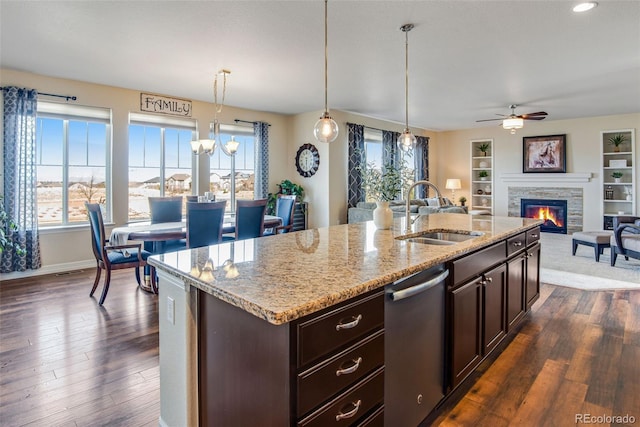 kitchen featuring dark wood-type flooring, dark brown cabinetry, dishwasher, a fireplace, and a sink