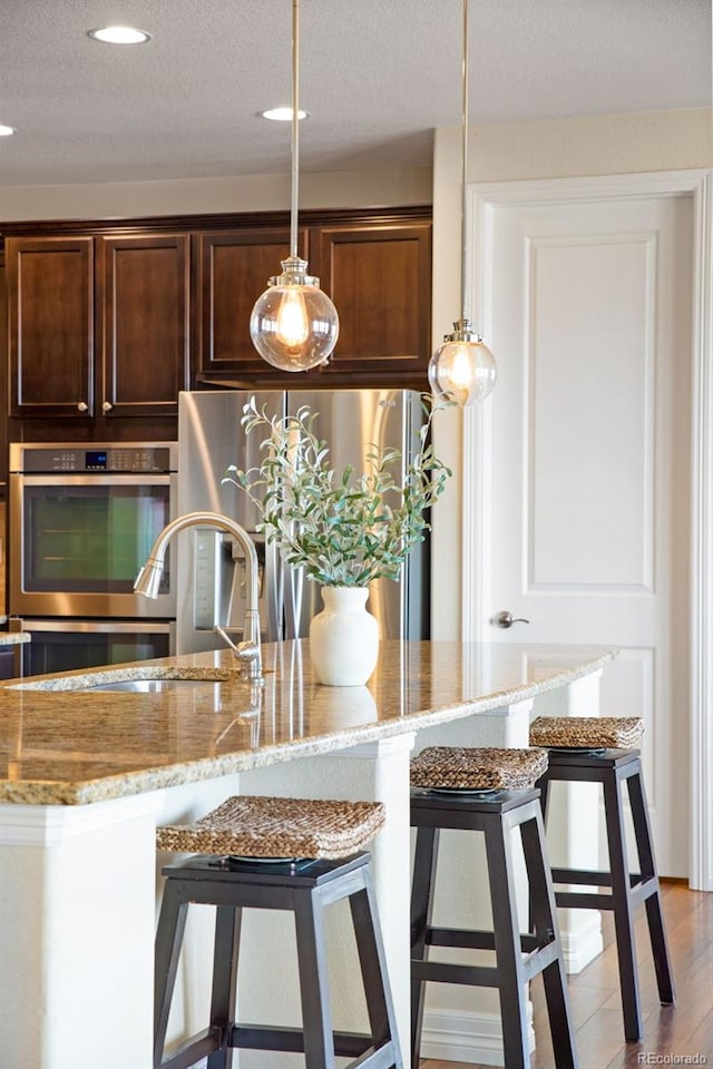 kitchen featuring light stone counters, appliances with stainless steel finishes, and a breakfast bar