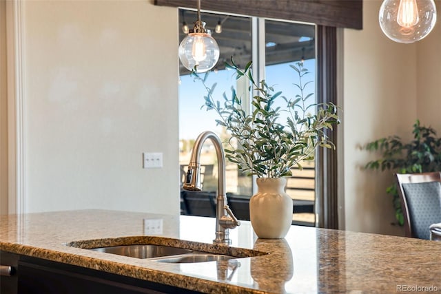 interior details featuring hanging light fixtures, stone countertops, and a sink