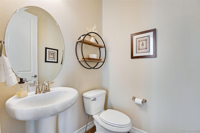 bathroom featuring toilet, baseboards, and a sink