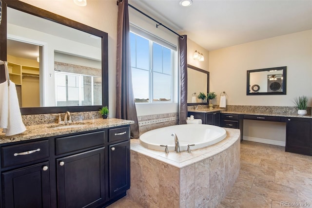 bathroom with vanity, a stall shower, stone finish flooring, a walk in closet, and a garden tub