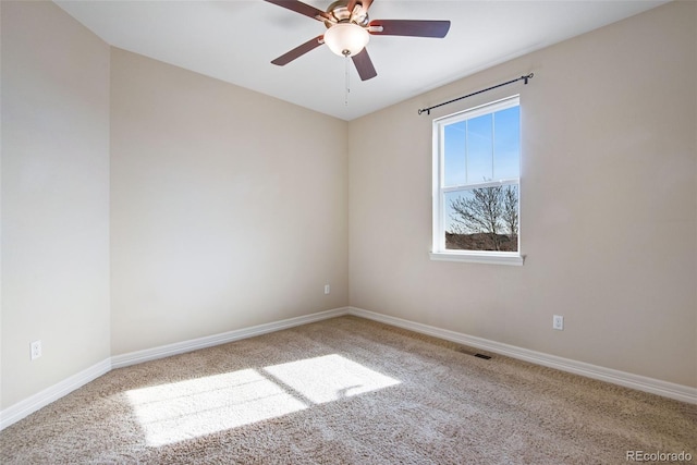 carpeted spare room with visible vents, baseboards, and ceiling fan