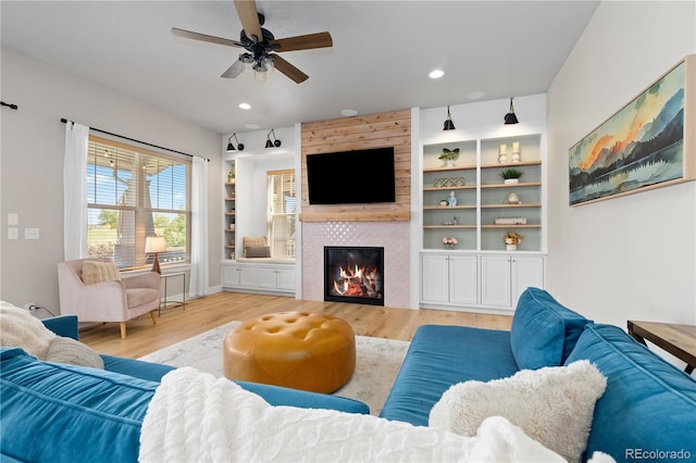 13729 Vallejo Loop, Broomfield, CO 80023 - living area with a tile fireplace, light wood-style floors, ceiling fan, recessed lighting, and built in features