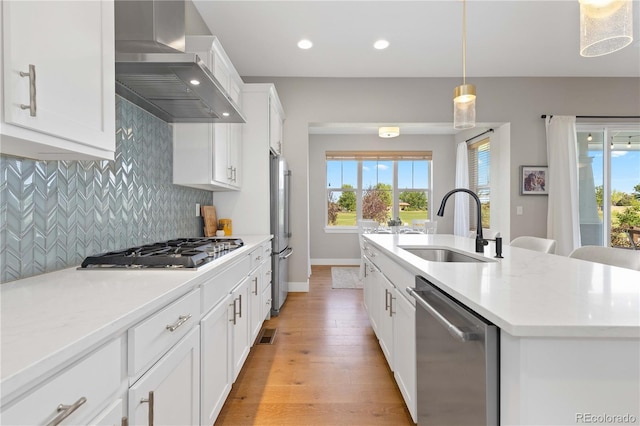 13729 Vallejo Loop, Broomfield, CO 80023 - kitchen with appliances with stainless steel finishes, wall chimney range hood, light wood-style flooring, tasteful backsplash, and a center island with sink