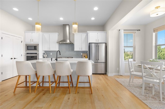 13729 Vallejo Loop, Broomfield, CO 80023 - kitchen with appliances with stainless steel finishes, wall chimney range hood, tasteful backsplash, a kitchen breakfast bar, and a center island with sink