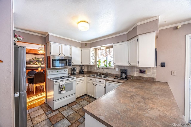 kitchen with appliances with stainless steel finishes, tasteful backsplash, white cabinetry, sink, and ornamental molding