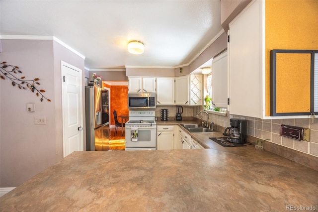 kitchen featuring sink, white cabinets, backsplash, ornamental molding, and stainless steel appliances