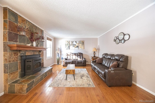 living room with hardwood / wood-style flooring, ornamental molding, a textured ceiling, and a wood stove