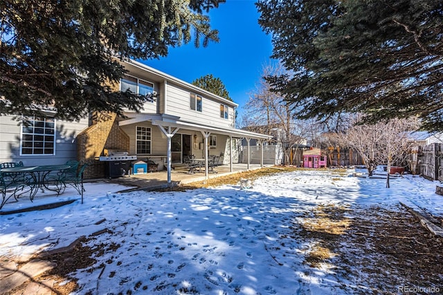 snow covered house featuring a patio