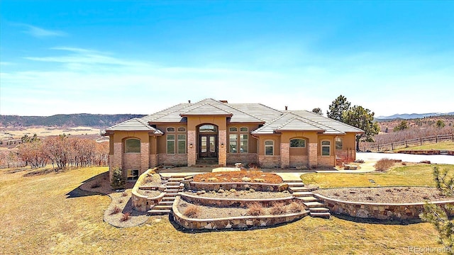 view of front of property featuring a tile roof, a front yard, a mountain view, and stucco siding