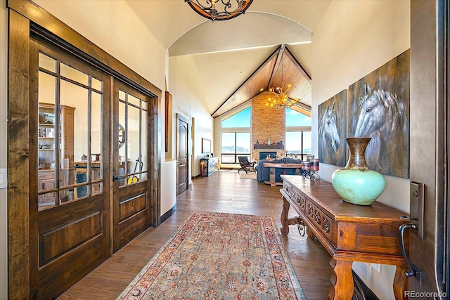 hall with wood-type flooring, an inviting chandelier, high vaulted ceiling, and french doors
