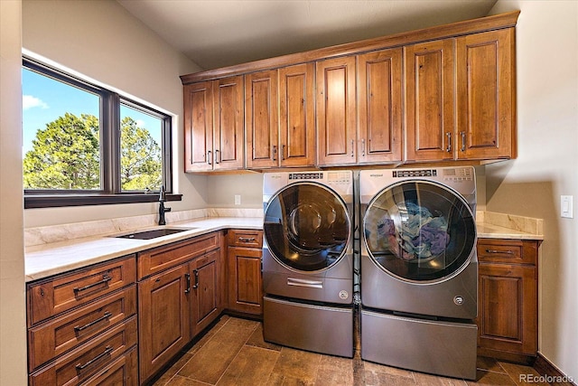 clothes washing area with washing machine and clothes dryer, cabinet space, and a sink