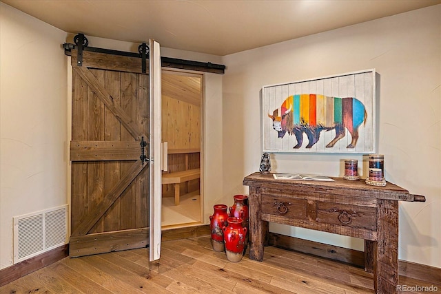 interior space with wood finished floors, visible vents, and a barn door