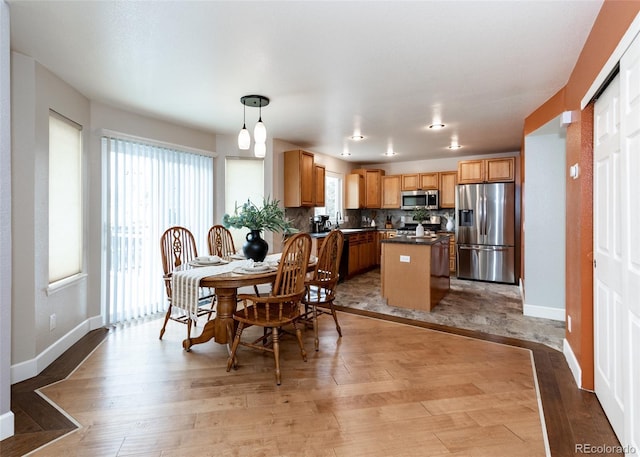 dining space featuring baseboards and light wood-style flooring