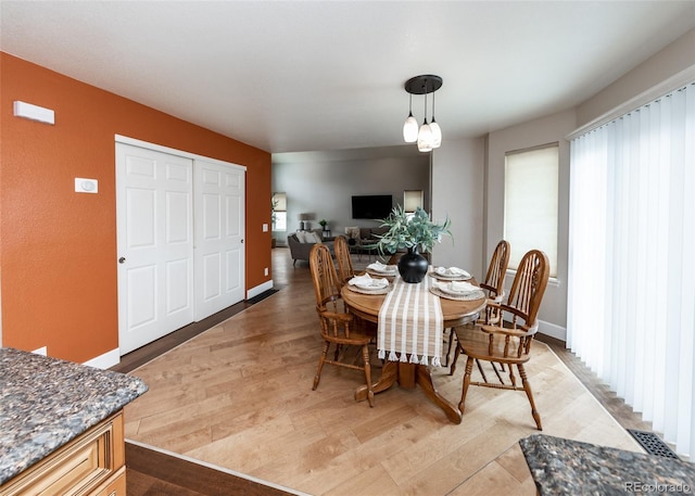 dining space featuring light wood finished floors, visible vents, and baseboards