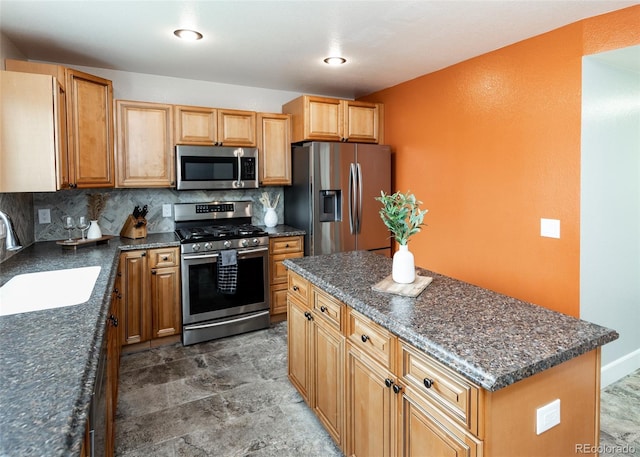 kitchen with a kitchen island, stainless steel appliances, tasteful backsplash, dark stone countertops, and a sink