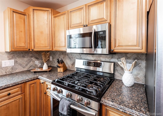 kitchen featuring tasteful backsplash, dark stone counters, and appliances with stainless steel finishes