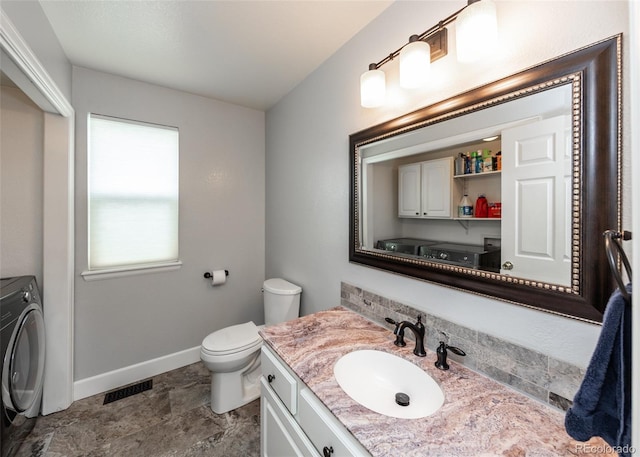 bathroom featuring baseboards, toilet, visible vents, vanity, and washer / clothes dryer