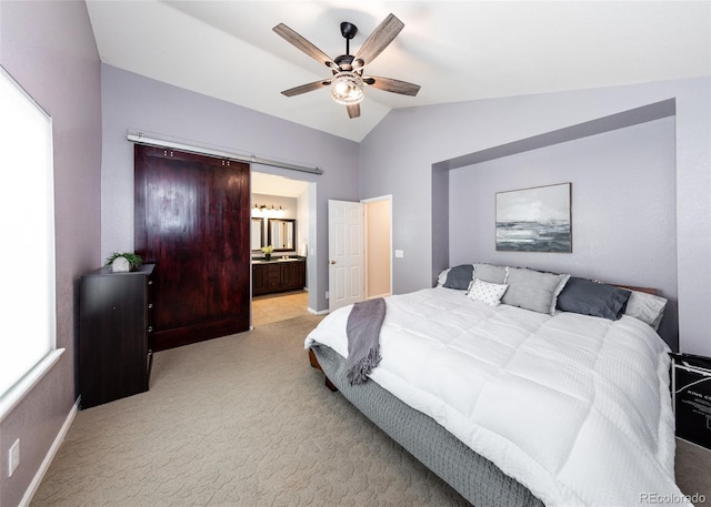 bedroom featuring vaulted ceiling, connected bathroom, a barn door, light colored carpet, and baseboards