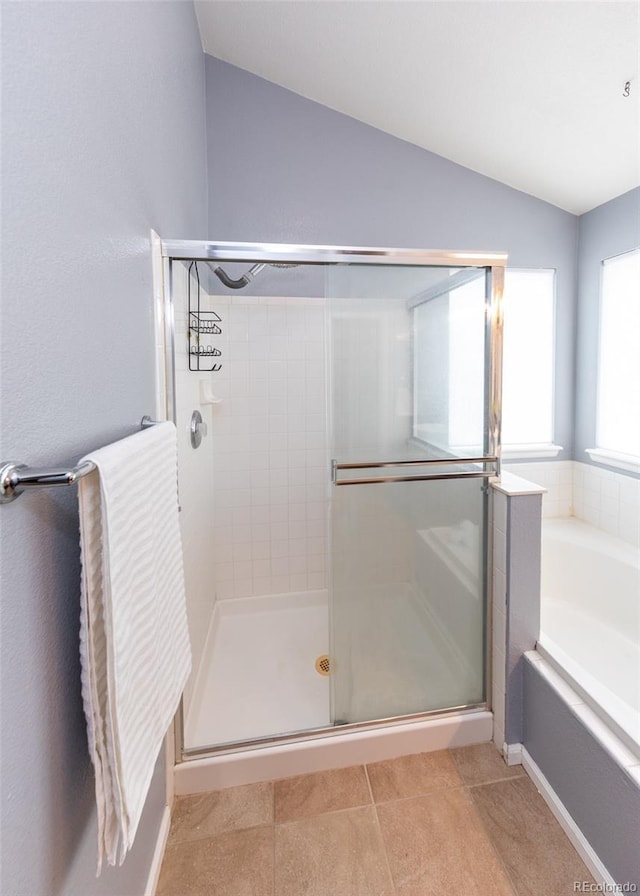 bathroom with tile patterned flooring, a stall shower, a garden tub, and lofted ceiling