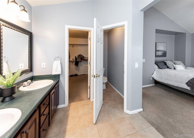 full bathroom with double vanity, toilet, tile patterned floors, a sink, and lofted ceiling