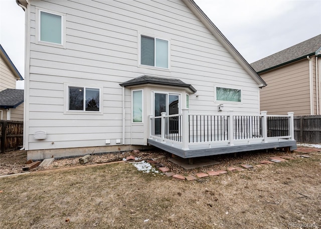 rear view of house with fence, a wooden deck, and a yard