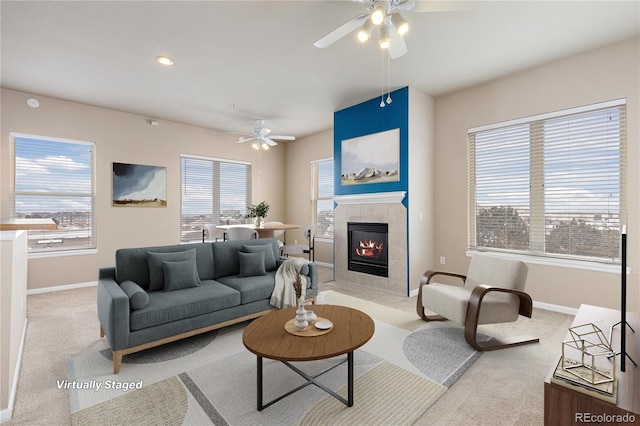 carpeted living room featuring a tiled fireplace and ceiling fan