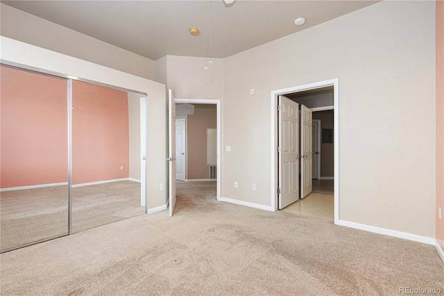 unfurnished bedroom with light colored carpet and a closet