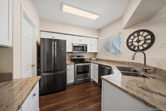 kitchen with stainless steel appliances, light stone countertops, sink, and white cabinets