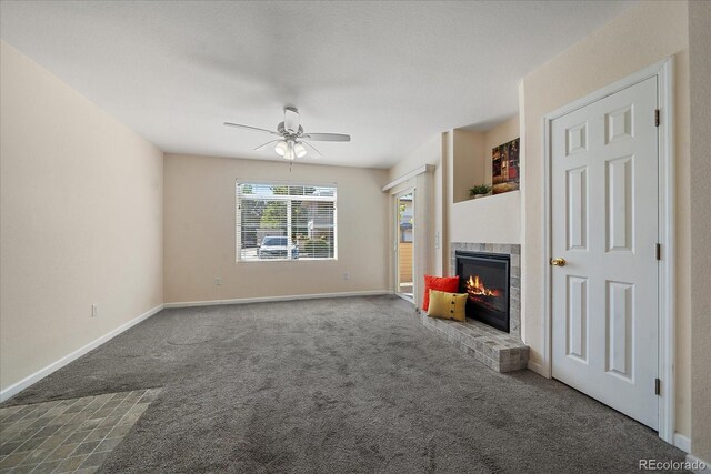 unfurnished living room with carpet, ceiling fan, baseboards, and a tile fireplace