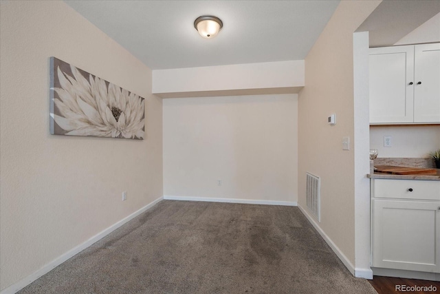 unfurnished dining area featuring carpet floors, visible vents, and baseboards