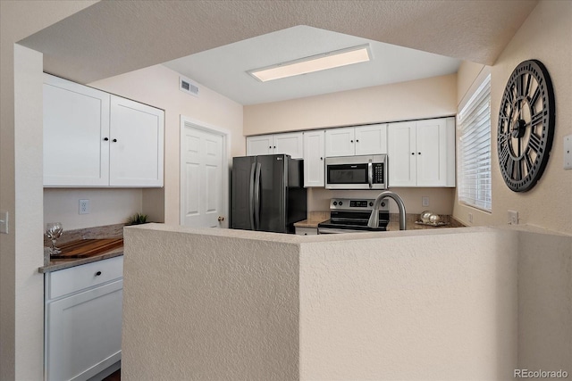 kitchen featuring a peninsula, appliances with stainless steel finishes, visible vents, and white cabinets