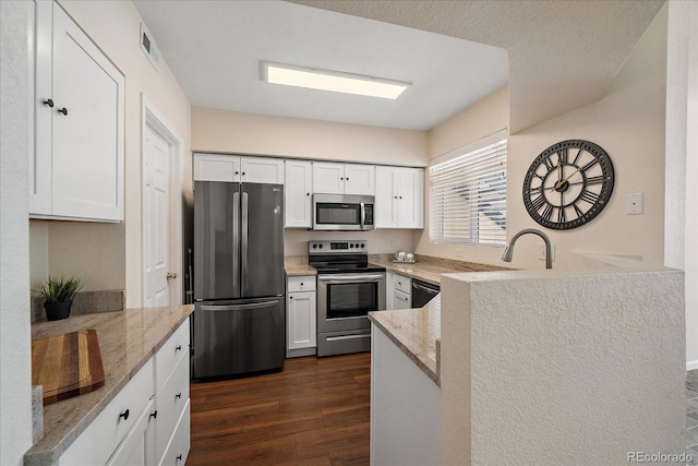 kitchen with stainless steel appliances, visible vents, white cabinets, light stone countertops, and dark wood finished floors