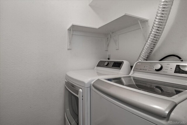 laundry area featuring laundry area, a textured wall, and washing machine and clothes dryer