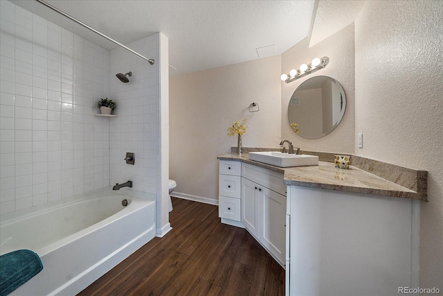 full bathroom featuring a textured wall, toilet, wood finished floors, a textured ceiling, and vanity