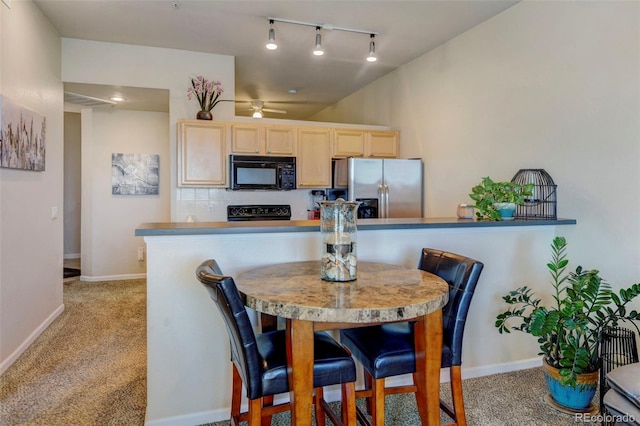 kitchen with light brown cabinets, track lighting, ceiling fan, black appliances, and light colored carpet