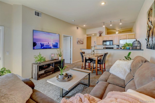 living room featuring rail lighting, light carpet, and ceiling fan