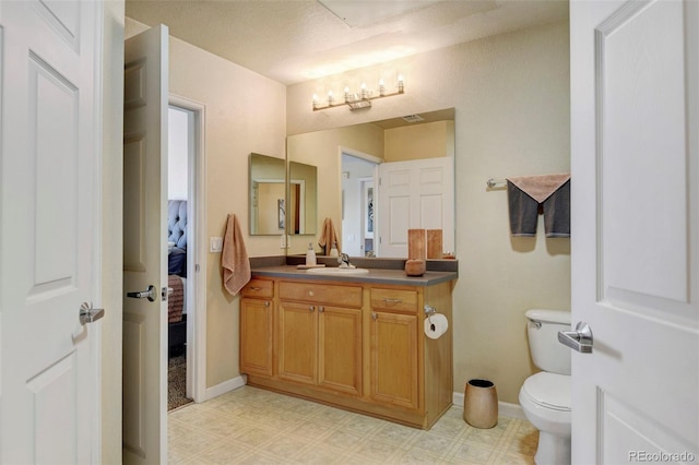 bathroom with vanity, toilet, and a textured ceiling