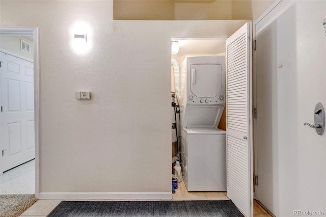 washroom featuring light tile patterned floors and stacked washer and clothes dryer