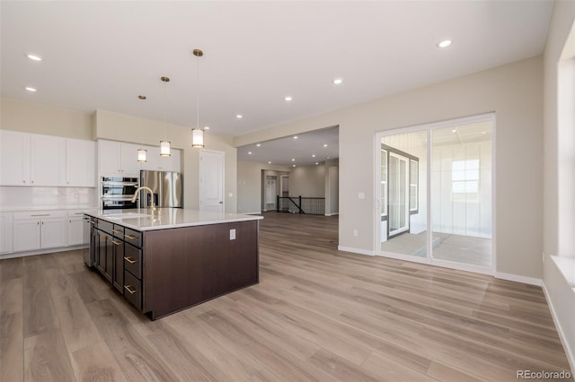 56159 E Tomahawk Ave, Strasburg, CO 80136 - kitchen with appliances with stainless steel finishes, white cabinetry, light countertops, light wood-style flooring, and recessed lighting