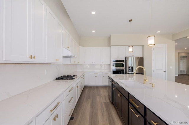 56159 E Tomahawk Ave, Strasburg, CO 80136 - kitchen featuring stainless steel appliances, a sink, white cabinets, wood finished floors, and recessed lighting