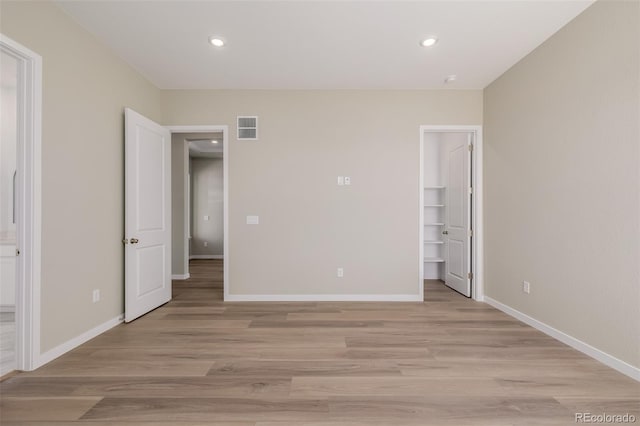 56159 E Tomahawk Ave, Strasburg, CO 80136 - unfurnished bedroom featuring light wood-style flooring, baseboards, recessed lighting, a spacious closet, and connected bathroom