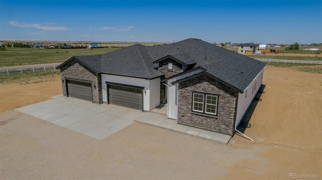56159 E Tomahawk Ave, Strasburg, CO 80136 - view of front of house featuring stone siding, fence, driveway, a garage, and roof with shingles