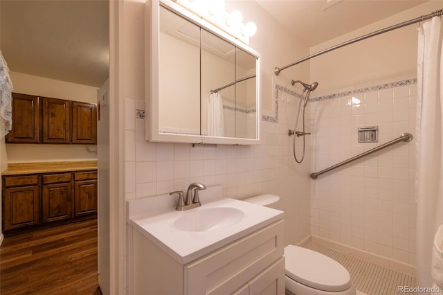 971 Elm Pl, Thornton, CO 80229 - bathroom featuring a tile shower, tile walls, vanity, toilet, and wood finished floors