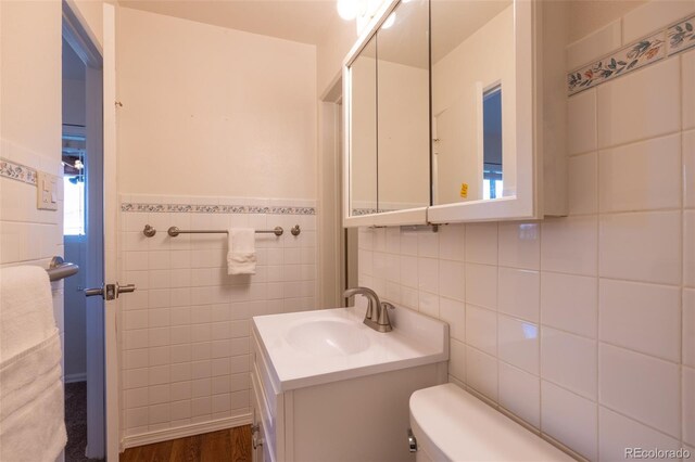 971 Elm Pl, Thornton, CO 80229 - bathroom with tile walls, toilet, vanity, and wood finished floors